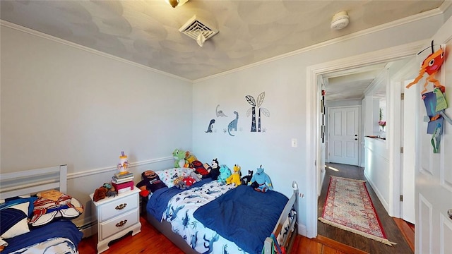 bedroom featuring visible vents, wood finished floors, and crown molding