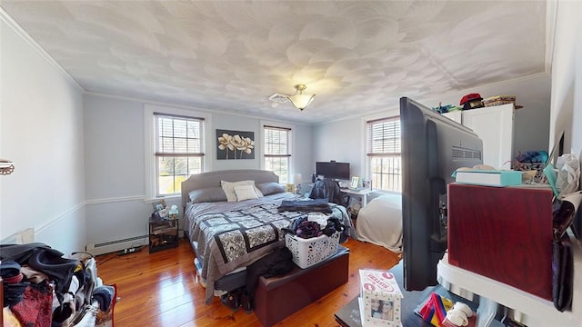 bedroom featuring baseboard heating, crown molding, visible vents, and wood-type flooring