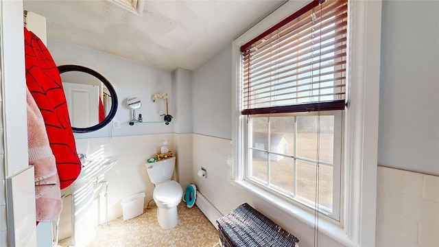 bathroom featuring wainscoting, toilet, and a baseboard radiator