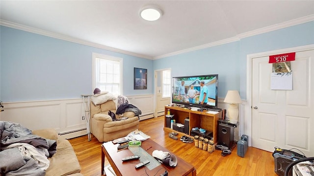 living room with baseboard heating, wood finished floors, wainscoting, and crown molding