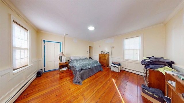 bedroom featuring baseboard heating, crown molding, and light wood finished floors