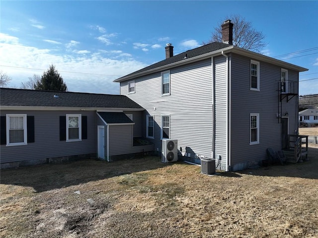 back of property featuring ac unit, central air condition unit, a yard, and a chimney