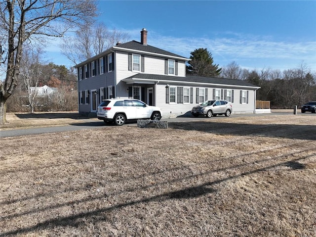 american foursquare style home featuring a front yard and a chimney