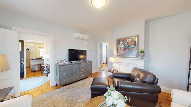 living room with baseboards, wood-type flooring, and an AC wall unit