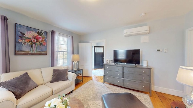 living area featuring baseboards, light wood-type flooring, and a wall mounted AC