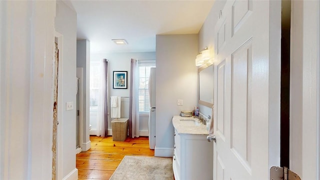 bathroom with baseboards, wood-type flooring, and vanity