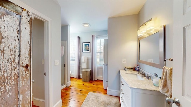 full bath featuring vanity, baseboards, and wood-type flooring