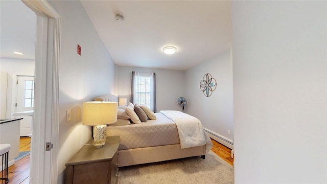 bedroom with wood finished floors and baseboard heating