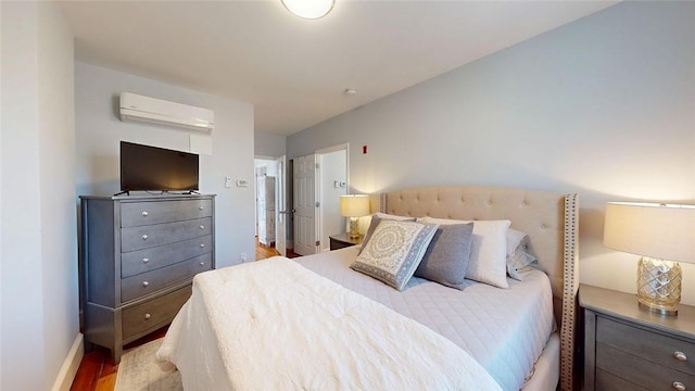 bedroom featuring baseboards, a wall mounted AC, and light wood-style floors