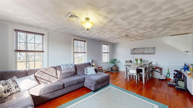 living room featuring a wealth of natural light, visible vents, a textured ceiling, and hardwood / wood-style flooring