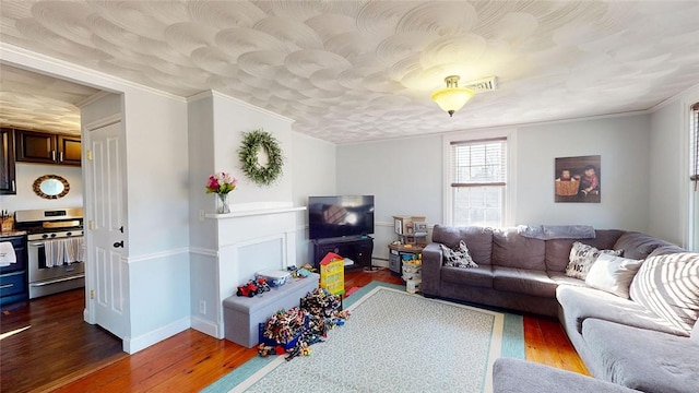 living room with dark wood finished floors, visible vents, baseboards, and ornamental molding