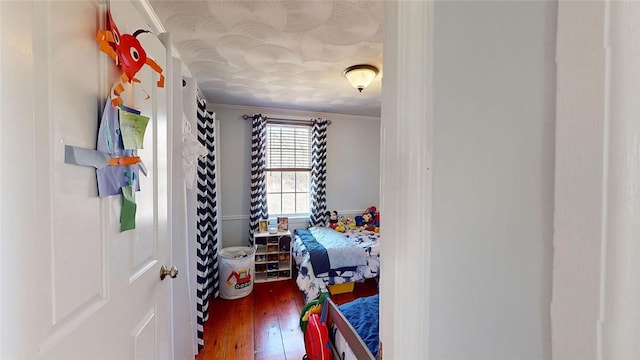 bedroom featuring ornamental molding and wood finished floors