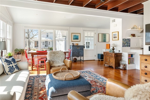 living room featuring visible vents, lofted ceiling, and wood finished floors