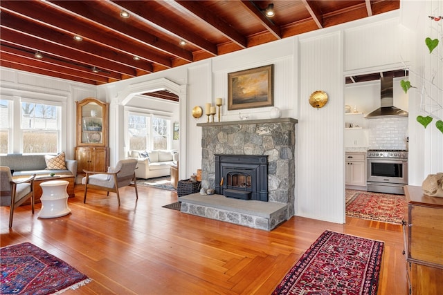 living room with beamed ceiling, wood finished floors, and a healthy amount of sunlight