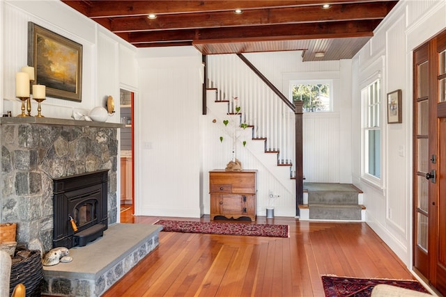 interior space with baseboards, stairway, wood-type flooring, and beamed ceiling