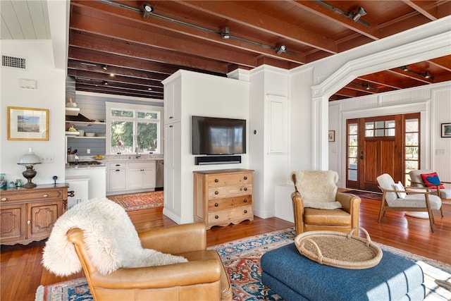 living area featuring visible vents, a healthy amount of sunlight, beamed ceiling, and hardwood / wood-style flooring