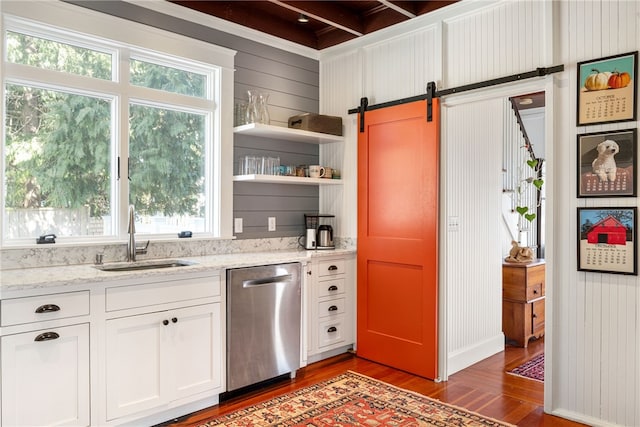 kitchen with open shelves, dark wood finished floors, a barn door, stainless steel dishwasher, and a sink