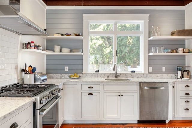 kitchen with a sink, stainless steel appliances, wall chimney exhaust hood, and open shelves