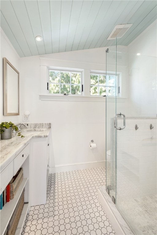 full bath with visible vents, baseboards, vaulted ceiling, a stall shower, and vanity