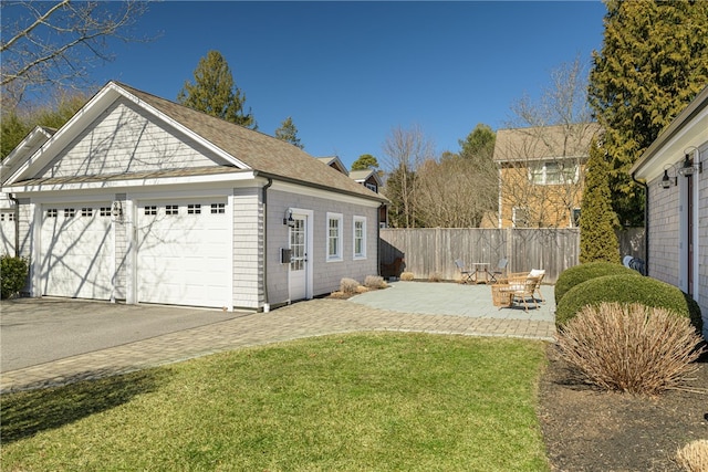 view of yard with a patio area, an outbuilding, aphalt driveway, and fence