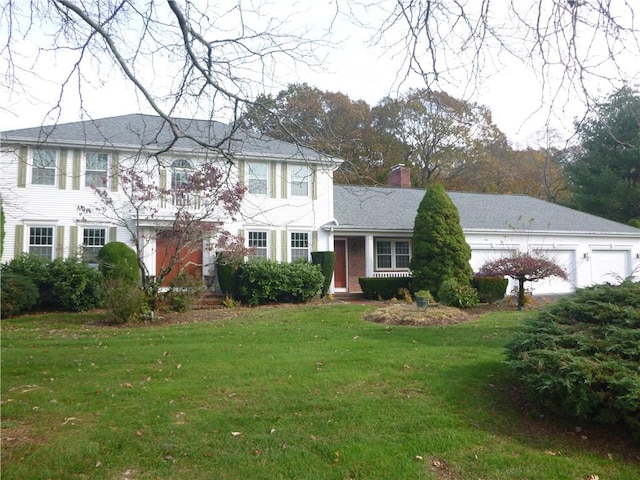 view of front of house with a garage, a chimney, and a front yard