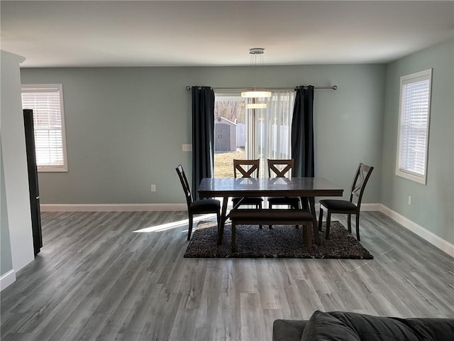 dining space with a chandelier, baseboards, and wood finished floors