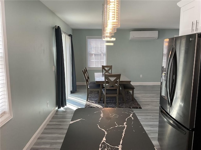 dining area with baseboards, a wall unit AC, and wood finished floors