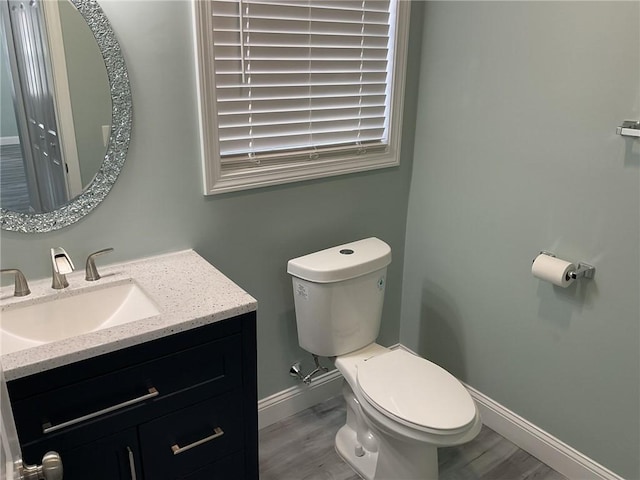 bathroom with vanity, toilet, wood finished floors, and baseboards