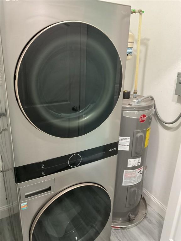 laundry area featuring laundry area, stacked washer and clothes dryer, electric water heater, and baseboards