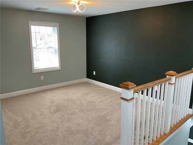 empty room featuring visible vents, baseboards, and light colored carpet