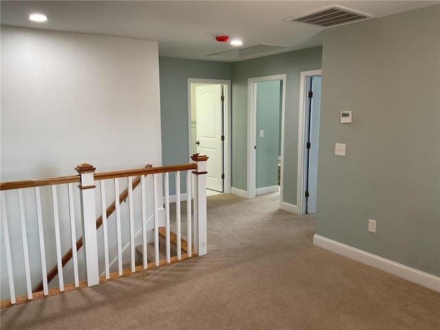 hallway featuring visible vents, baseboards, recessed lighting, carpet flooring, and an upstairs landing