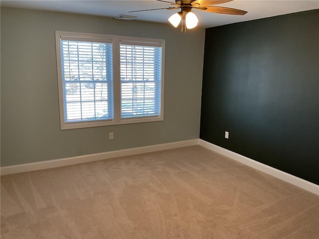 spare room with light carpet, visible vents, baseboards, and ceiling fan