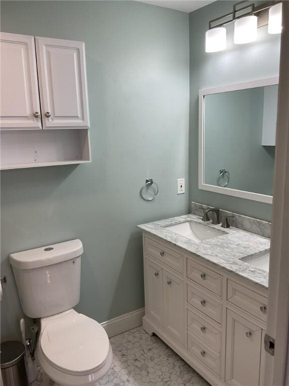 bathroom featuring toilet, vanity, and baseboards