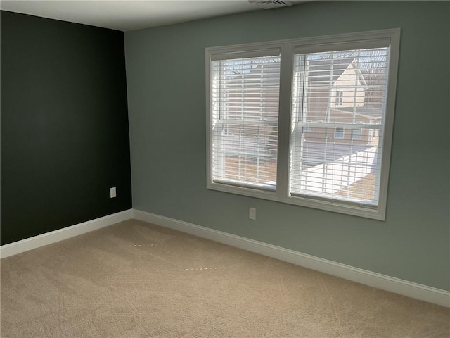 empty room with a wealth of natural light, light colored carpet, and baseboards