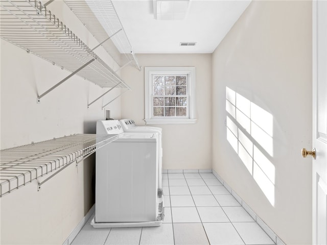 clothes washing area featuring light tile patterned flooring, laundry area, washer and dryer, and visible vents