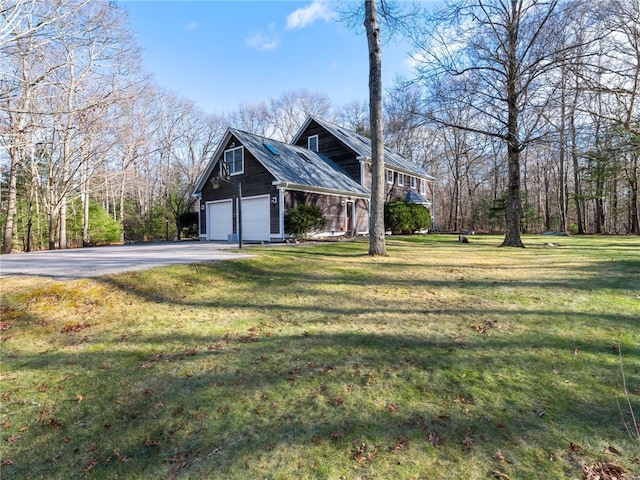 view of side of property featuring aphalt driveway, a yard, and a garage