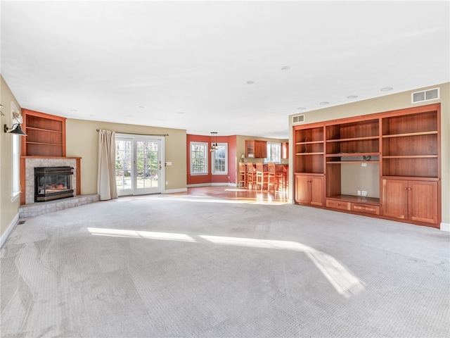 unfurnished living room featuring visible vents, light carpet, and a glass covered fireplace