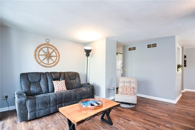 living room featuring visible vents, baseboards, and wood finished floors