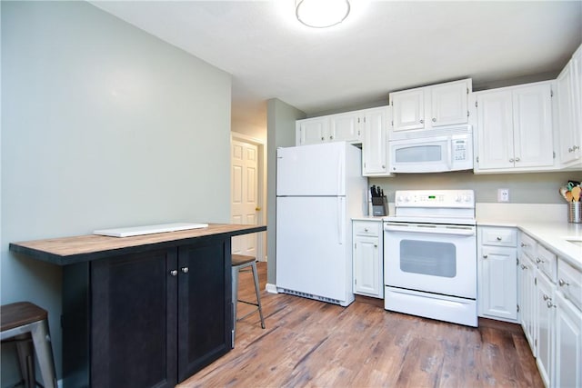 kitchen featuring a kitchen bar, dark wood finished floors, white cabinetry, white appliances, and light countertops