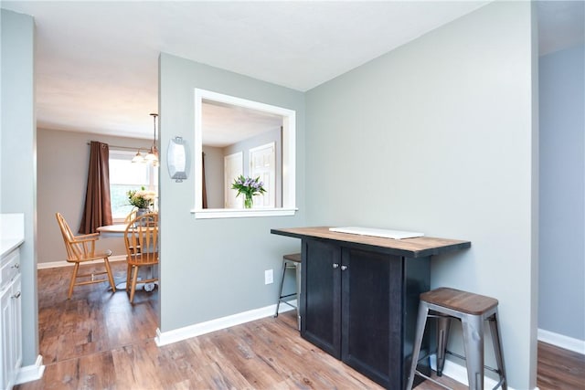 interior space featuring baseboards, a notable chandelier, and wood finished floors