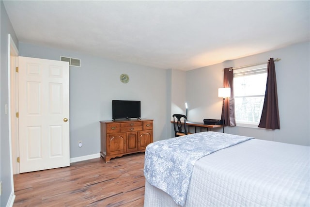 bedroom featuring wood finished floors, visible vents, and baseboards