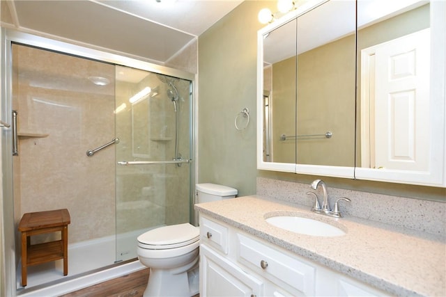 bathroom with vanity, a shower stall, toilet, and wood finished floors