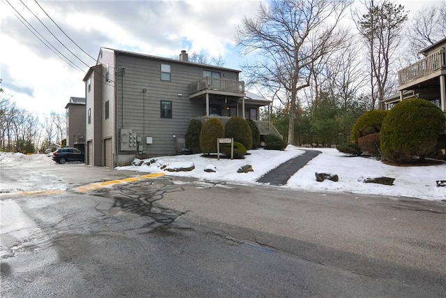 snow covered property with a balcony and a chimney