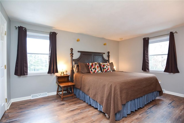 bedroom featuring visible vents, multiple windows, and wood finished floors