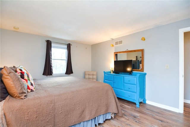 bedroom featuring visible vents, baseboards, and wood finished floors