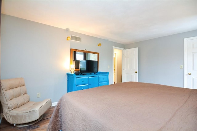 bedroom featuring wood finished floors, visible vents, and baseboards