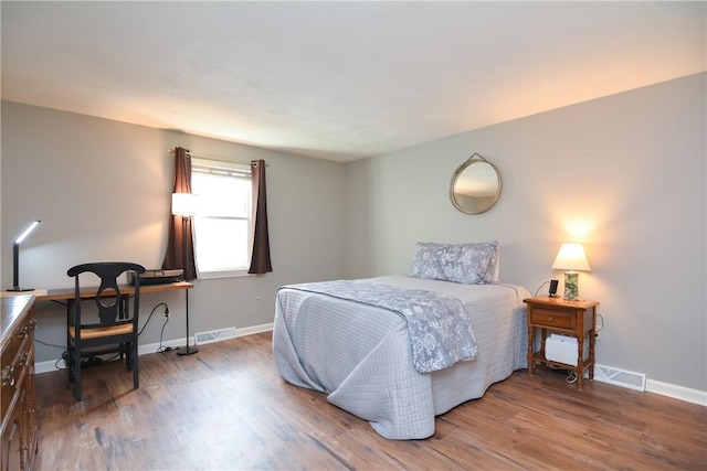 bedroom with visible vents, baseboards, and wood finished floors