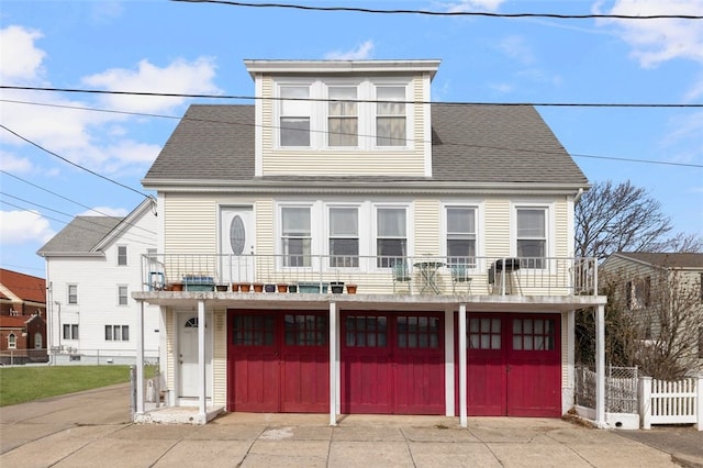 view of front of home with a garage, a balcony, and a shingled roof