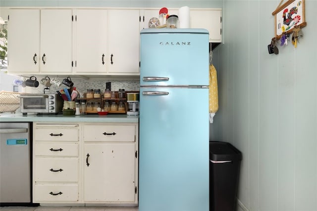 kitchen with stainless steel dishwasher, white cabinetry, freestanding refrigerator, a toaster, and light countertops