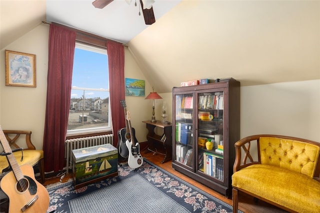 living area featuring a ceiling fan, wood finished floors, radiator heating unit, and vaulted ceiling